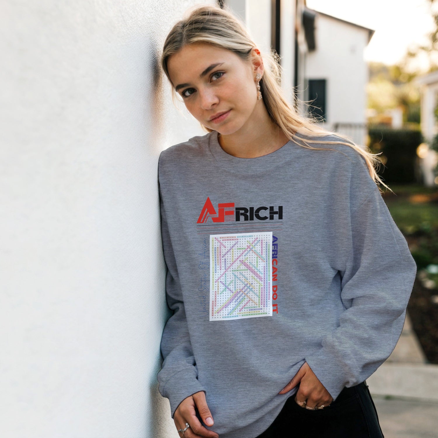 Young boys and girls are playing basketball, while in the foreground, a beautiful Black girl with clear skin, wearing a blue AFRICH® Crossword Sweatshirt, holds a basketball in her right hand, looking toward the right corner.